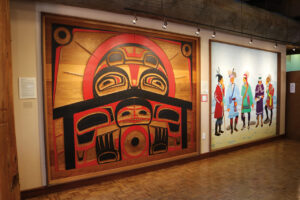 A wooden art installation on the wall depicting the Tsimshian legend of the origin of daylight.