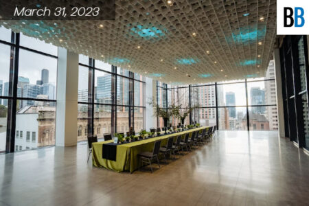 A role of tables inside the SCC Summit building. Glass windows all over the room. Seeing outside the city of Seattle. Green drape table cloth.