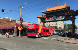 A red bus moves along the street under the ornate Chinatown Gate in Seattle.