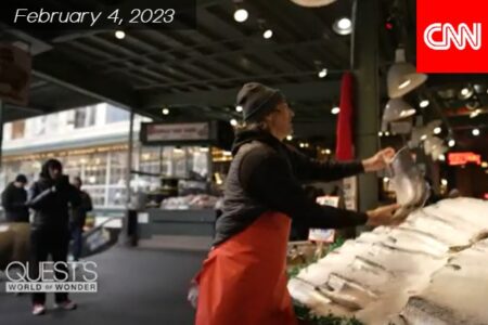 A fishmonger tosses a big fish at Pike Place Market