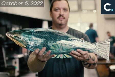 Artist Dan Friday holds up a glass art piece of his - a beautiful blown glass fish.