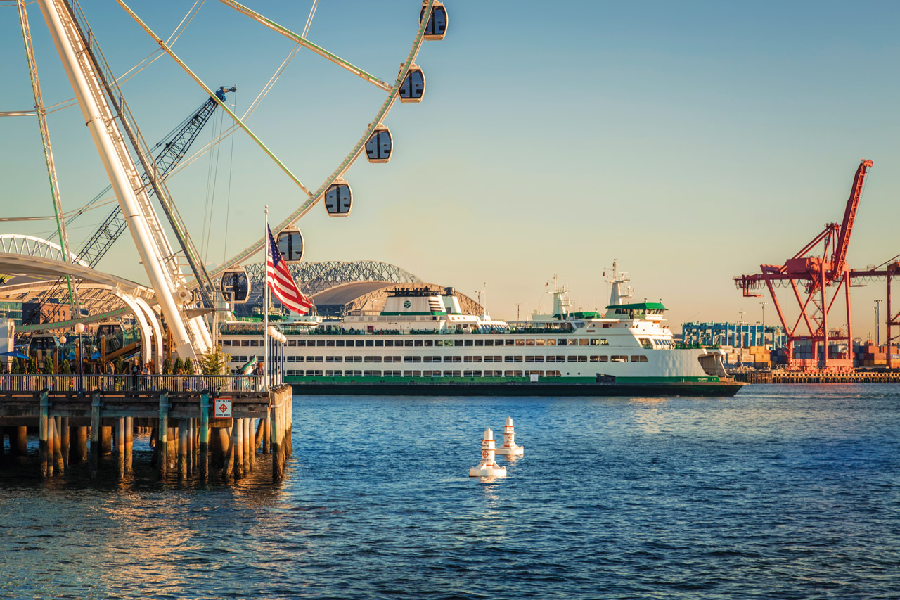 A ferry leaving the Seattle terminal with a Ferris wheel in the foreground