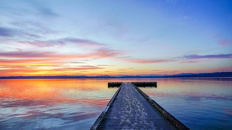 Sunset colors reflected from the sky to the water with a lone, empty t-dock extending away from the camera