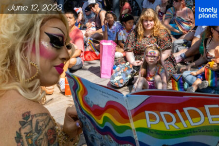 Drag queen reading to a group of children and women.