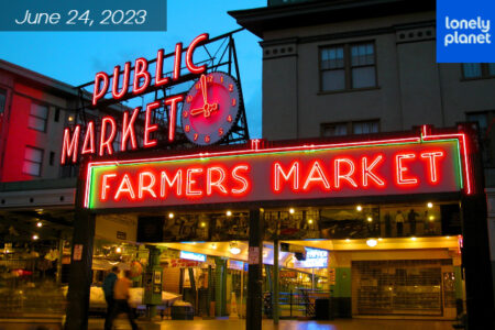 Red lighted Pike Place Market Farmers Market sign is displayed on a evening night in Seattle.