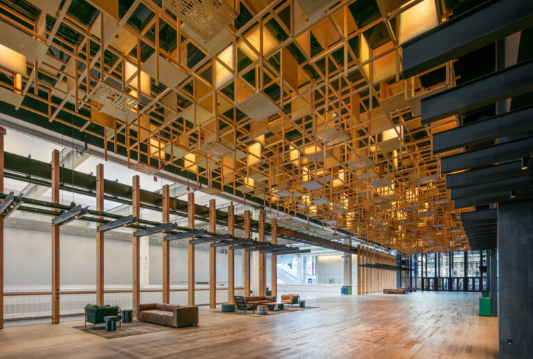 Building atrium with couches and tables underneath a wooden chandelier sculpture