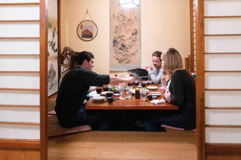 A photo of people sitting on the ground around a table at Maneki restaurant.