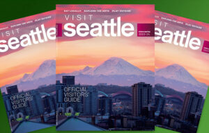 A photo of the cover of Visit Seattle's 2023-24 Winter/Spring Official Visitors' Guide displayed three times. The photo is of Mount Rainier which is cast in purple light with an orange and pink sunset behind it. The city is in the foreground with lit up buildings including the arches above T-Mobile Park, Lumen Field, and the sign on Climate Pledge Arena.