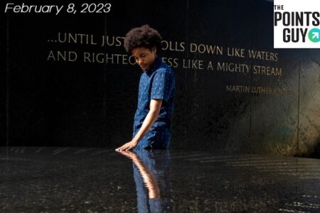 Young black man touches the surface of a Black History Memorial