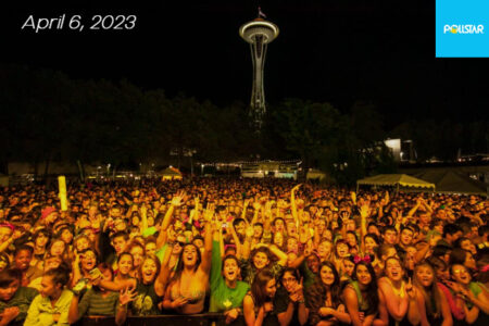 A crowd of people cheering with the space needle in the background.