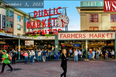 People walking around Pike Place Market. Blue sunny skies and people walking in front of the pike sign.