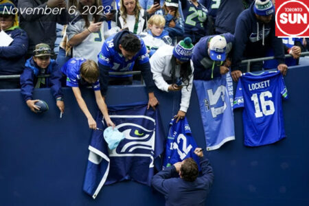 Seahawks GM John Schneider signs autographs for fans before his team’s game against the Cardinals on Sunday, Oct. 22, 2023, in Seattle. A crowd in sports stand asking for autographs. Wearing blue Seahawks gears.