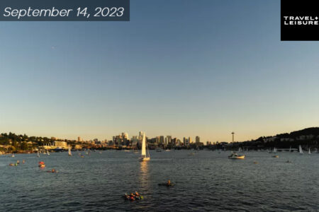 Sun setting and a view of the Seattle lake. Space Needle shown in the far back very tiny. Boat/yachts out in the lake.