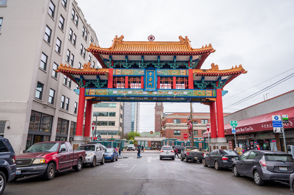An ornate red Chinatown Gate bridges a street lines with cars.